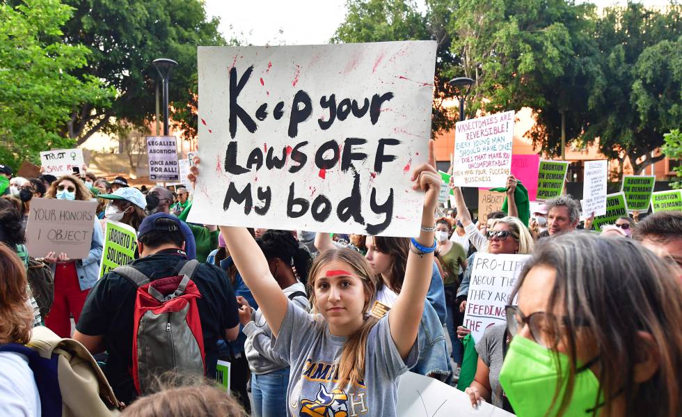 Mujeres y hombres protestan en Los Angeles el 3 de mayo de 2022 tras la filtración de un borrador del Tribunal Supremo de EE UU sobre tumbar el derecho al aborto. El cartel dice "quita tus leyes de mi cuerpo".