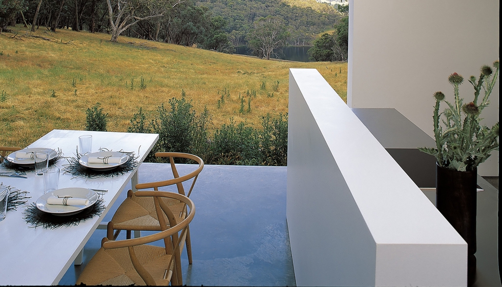 Junto al salón, el comedor comparte vistas y doble altura y da la espalda a la cocina abierta. Las sillas de madera de haya son otro clásico danés: el modelo Wishbone diseñado por Hans Wegner y producido, desde hace medio siglo, por Carl Hansen & Son.