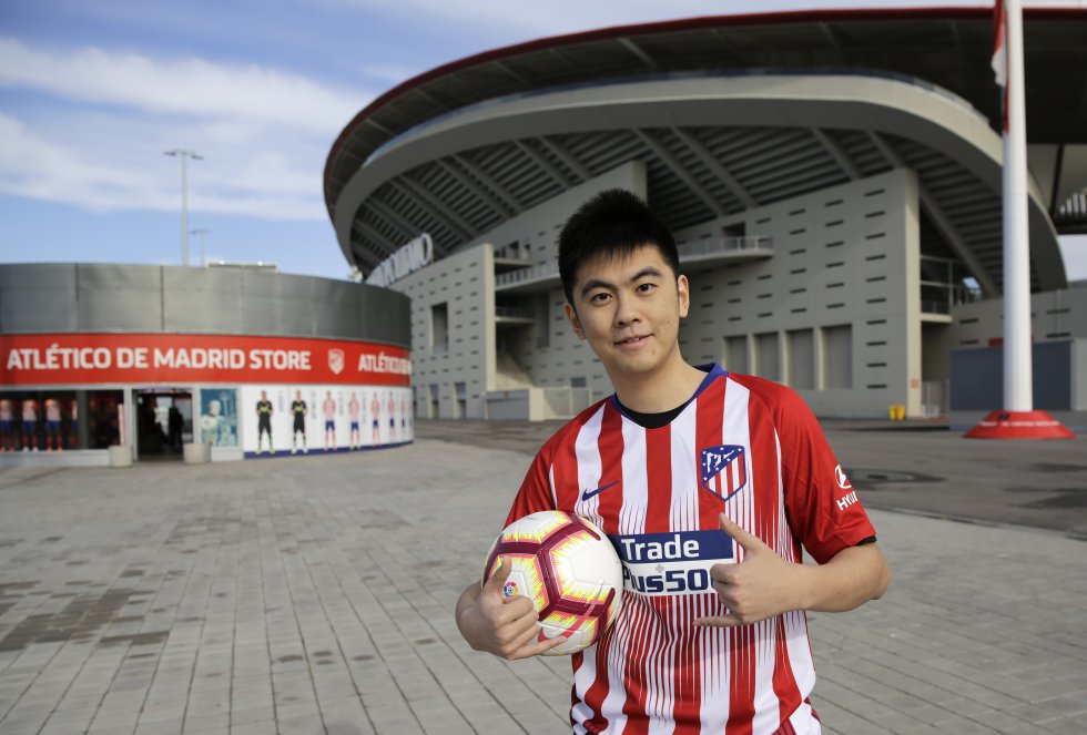 Jiacheng Li, un joven chino de 25 años, saca de la mochila una camiseta preservada cuidadosamente en una bolsa hermética. Es la elástica del Atlético de Madrid. A la espalda, el nombre de Saúl Ñíguez y la rúbrica del propio jugador. Li, en las inmediaciones del Wanda Metropolitano, explica en un español aún titubeante que llegó hace dos años para hacer un máster de gestión deportiva. Se apuntó al club nada más llegar. El ADN colchonero ya viajaba en su maleta. “Fernando Torres era mi jugador preferido. Lo seguía en China desde la época en que lo entrenaba Luis Aragonés”, explica. Socio y abonado, al igual que su novia, Li posa con orgullo frente al Wanda e imita las celebraciones inspiradas en el videojuego Fornite de Griezmann, su ídolo actual, y las caras del Cholo cuando arenga a sus jugadores. Y con dos palabras resume lo que siente al ver a los rojiblancos batirse en el estadio: “Emoción y pasión”.