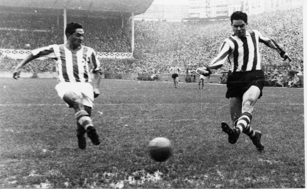 La competición ha asistido hasta ahora a 142 duelos entre el Athletic y la Real con este balance: 58 victorias para los bilbaínos, 47 para los donostiarras y 37 empates. Es el tercer derbi con más historia tras los de Barcelona (168) y Madrid (162). Una película con 90 años de recorrido desde aquella primera escena en Atotxa, cuando las gradas aún eran menos altas que los tamarices, los árboles que pueblan el paseo de la Concha. Protagonizada por 20 apellidos —vascos, casi todos— que han escrito la historia del fútbol euskaldún: intensidad y goles en el césped; pasión y respeto en la grada. Estas imágenes recuerdan algunos de sus grandes momentos, un viaje del blanco y negro al color, del No-Do a la alta definición. Hoy, las dos entidades miran al futuro desde sus nuevas casas: escenarios espectaculares para exportar la imagen de LaLiga por todo el planeta. ‘Zurigorris’ y ‘txuriurdines’ volverán a verse las caras este viernes, a las 21.00, en San Mamés. En la foto, Peporro, de la Real, y Arieta I, del Athletic, en Atotxa en la temporada 195859.