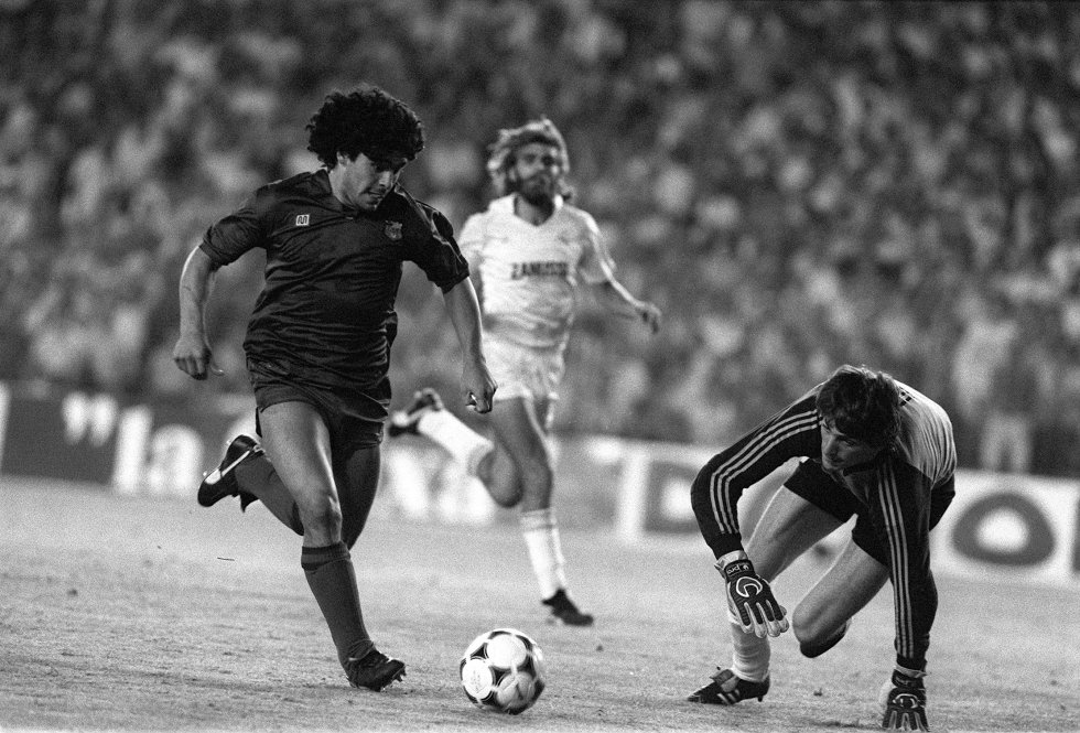 El FC Barcelona fichó a Diego Armando Maradona por 1.200 millones pesetas en 1982. Una hepatitis y una fractura de tobillo le permitieron jugar solo 58 partidos en dos años. Marcó 38 goles, dio 24 asistencias y alzó tres trofeos: Copa del Rey, Copa de la Liga y Supercopa de España. En 1984, se marchó al Nápoles de Italia. Regresó a España en la década del 90 para jugar en el Sevilla, bajo las órdenes de Carlos Bilardo, con quien había triunfado en el Mundial de 1986 con la albiceleste. En la imagen, Diego, a punto de anotarle un gol al Real Madrid, con la camiseta del Barcelona.