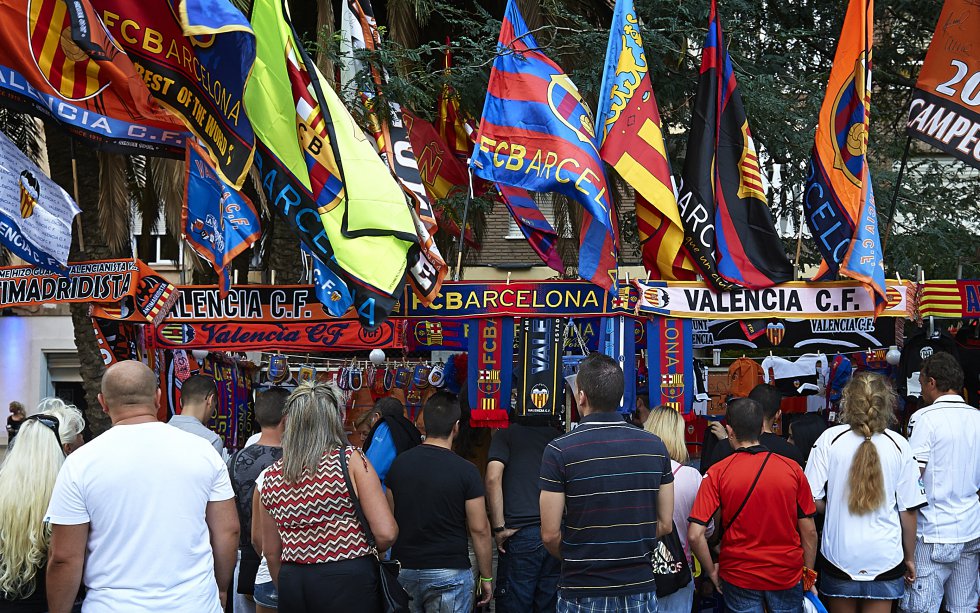 Fernando, Matías, Daniel, Iris o Ana viven del fútbol sin dar una patada a un balón. Cocinan tortillas de 22 huevos para la primera plantilla del Valladolid, venden miles de bufandas y banderas a las puertas de los estadios cada semana (arriba, imagen de Mestalla), hacen de guías turísticos con pequeños inversores extranjeros en Oviedo, pasean al Leganés por las redes sociales en todo el mundo o cuidan de la salud de los jugadores de Getafe… No se llaman Messi, Griezmann o Isco. Nunca salen en la portada de los periódicos. Nadie conoce sus historias. Más de 230.000 familias, como las de estas personas, se ganan la vida en España gracias al fútbol. Pero los beneficios de esta industria del entretenimiento global impactan, también, en la vida diaria de personas anónimas y en la economía del país. Los empleos directos e indirectos en torno al fútbol generan más del 1% del PIB español (según la consultora KPMG) y contribuyen con más de 1.300 millones en impuestos. LaLiga no es solo fútbol; es una marca en constante expansión y reinvención. Para Enrique Moreno, director de Marca Global de LaLiga, este deporte es relevante para el tejido social y productivo como palanca de crecimiento, de innovación y de internacionalización: “El negocio del fútbol y sus ingresos pueden tener un impacto muy positivo en la vida de las personas”. El mundo va camino de convertirse en el “nuevo terreno de juego” de LaLiga sin fronteras.