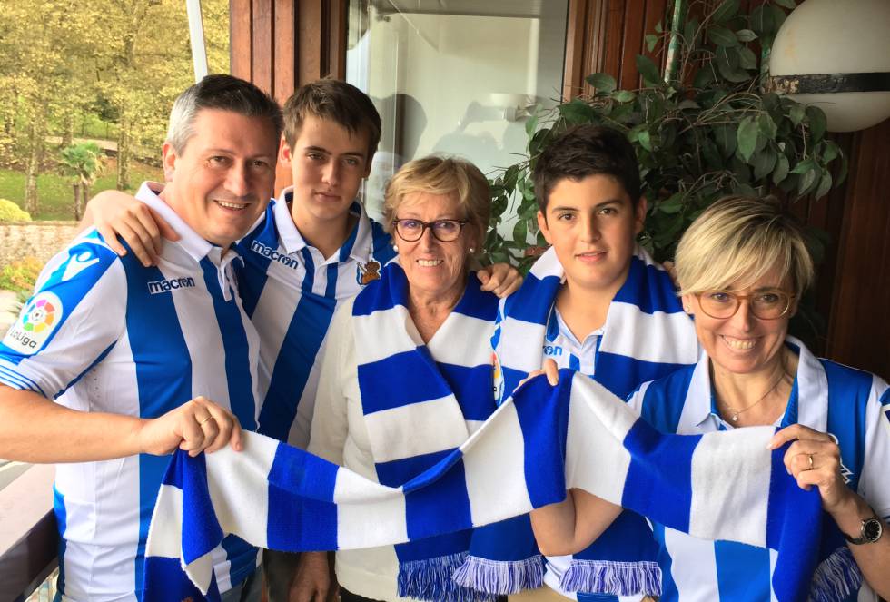 Ramón Barandiaran y Karmele Aguirre incluyeron el fútbol entre sus planes de fin de semana desde que empezaron a salir. El hecho de que esa chica fuera entusiasta de la Real Sociedad en un momento en el que no se veían muchas mujeres en Anoeta fascinaba a Ramón. “Le parecía la repanocha”, recuerda ahora Karmele, gestora administrativa de 53 años.   Ella proviene de una familia con tradición realista. Su madre, Arancha Arzalluz, de 79 años, también disfruta con la Real, un equipo que siempre ha tenido cerca, incluso físicamente. Durante décadas, los jugadores del club solían ir a su restaurante, el Urola, a comer antes de coger el avión para un desplazamiento. “Mi madre les abría el comedor antes, para ella eran sus niños”, cuenta Karmele. Pablo y Aitor, los hijos de Karmele y Ramón, han heredado esa pasión por la Real. “Empezamos a llevarlos con tres añitos y los hicimos socios a los cinco”, comenta Ramón. Ahora tienen 17 y 15 años, respectivamente, y el armario lleno de camisetas del club, una por cada temporada que han vivido junto a sus padres con los que, por ahora, van a seguir viendo los partidos. “Con la remodelación de Anoeta, tenían la oportunidad de recolocarse con sus amigos, pero han decidido quedarse con nosotros”, concluye Ramón, abogado de 50 años.   En la foto: de izquierda a derecha, Ramón Barandiaran, Pablo Barandiaran, Arantxa Arzalluz, Aitor Barandiaran y Karmele Aguirre.