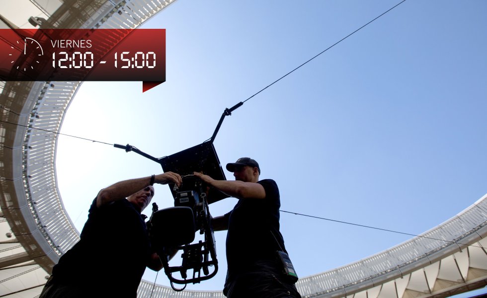 El montaje de la cámara aérea que sobrevolará el césped es muy laborioso. Primero se bajan los cables con las cuatro poleas que los sujetan con la ayuda de motores de 160 kilogramos. Los cables están anclados en cuatro puntos de la cubierta. Luego, a ras de césped, se inserta la cámara en ellos, en una maniobra que los técnicos Xavi Cardona y Luis Pascual ejecutan casi de memoria. La tecnología está presente ya en 11 de los 20 estadios de la máxima categoría, capaz de volar a una velocidad de 36Kmh tomando imágenes cenitales. Antes de las 14.00 horas Cardona y Pascual han completado el ensamblaje y están ya haciendo pruebas de vuelo. Ninguna otra liga utiliza esta técnica salvo en partidos concretos, de especial entidad, por eso “no hay nadie que haga tantas producciones aéreas como nosotros, unas 200 al año”, afirma Cardona.