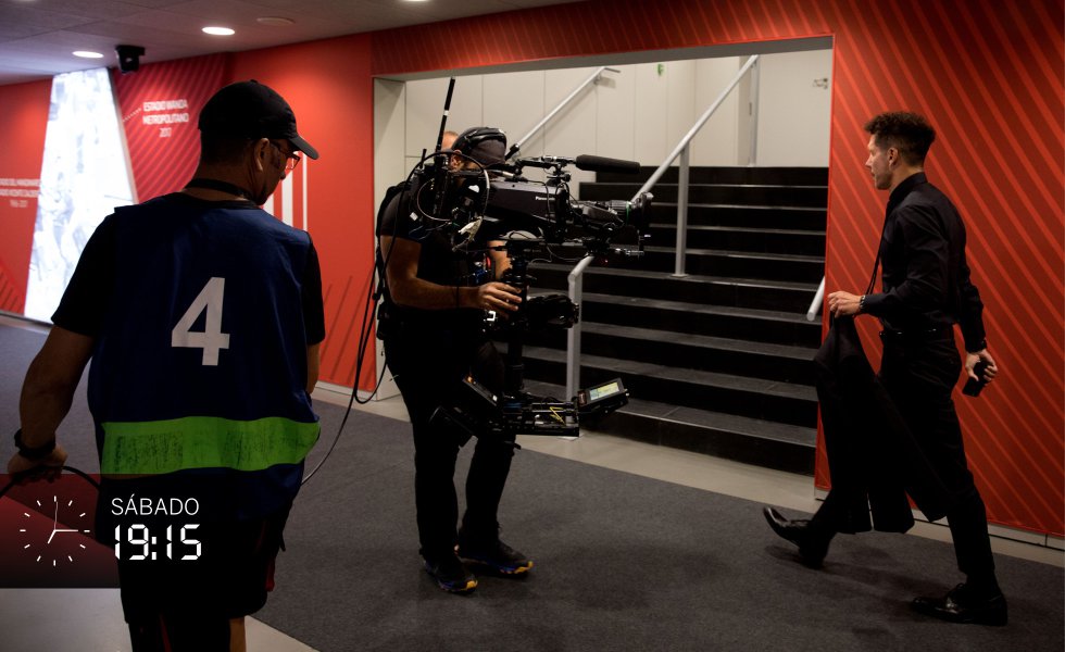 A las 19.15 del sábado llegan los autobuses de ambos equipos al estadio. Primero bajan los integrantes del Atlético de Madrid y se dirigen al vestuario local, luego los del Real Madrid que se encaminan al de visitantes. En ese pasillo desde el garaje los espera un técnico a cuestas con el equipamiento de una 'steady cam' (cámara estabilizada) que pesa casi 35 kilogramos, acompañado casi siempre de otro compañero que sujeta los cables para evitar que tropiece. Una caída con toda la carga podría dañar severamente el equipo. En la imagen, la entrada del entrenador del Atleti, Simeone.