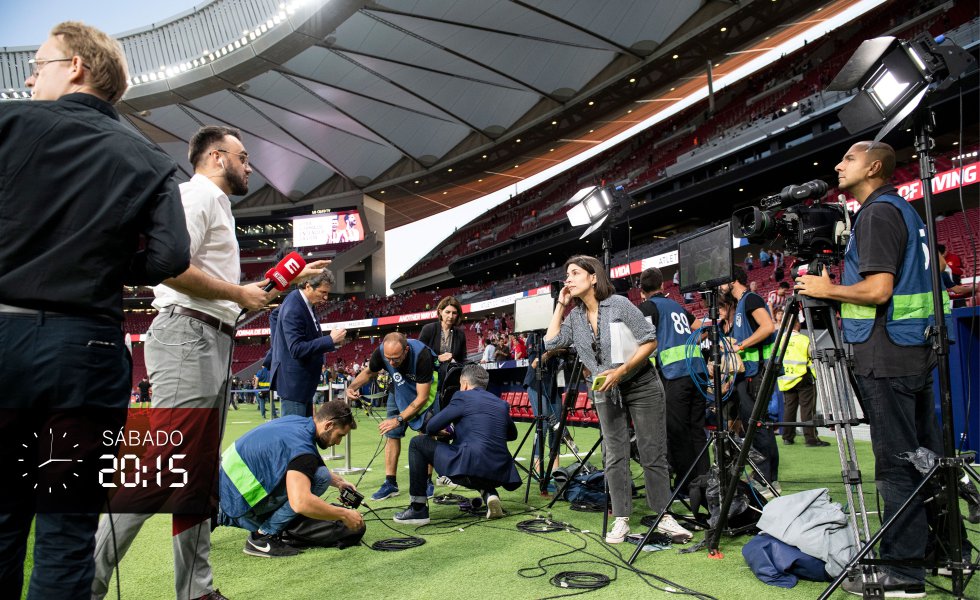 Falta poco más de una hora para que comience el partido y sobre el césped apenas quedan los periodistas acreditados. Hay dos puestos que técnicos de Mediapro han tenido que habilitar previamente para las cinco televisiones extranjeras, que deben repartirse el tiempo. De gestionar los turnos y coordinar todo se ocupa la productora Leticia Pasamontes, en la imagen, en el centro, con un teléfono en la oreja y otro en la mano, y con un portadocumentos bajo el brazo.