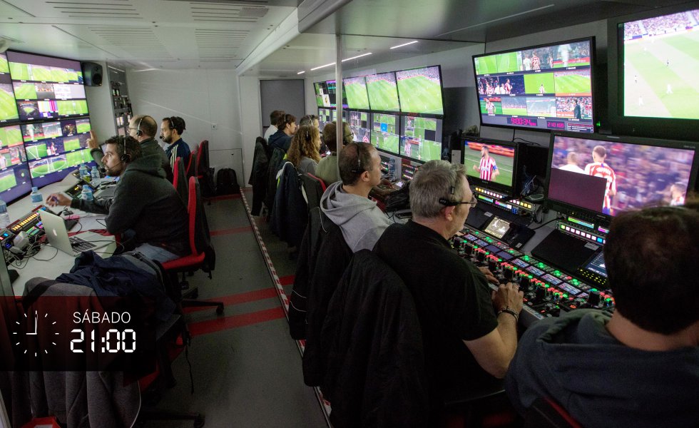 La unidad móvil está plagada de pantallas, botones, y de pares de ojos atentos a todos los detalles para componer el puzle de imágenes que será la retransmisión. Una docena de técnicos se reparten en dos filas. A la izquierda, el realizador con sus ayudantes. A la derecha, los técnicos que se encargan de las repeticiones. Nadie habla. La única voz que puede oírse es la del realizador. Durante dos horas la concentración es absoluta.