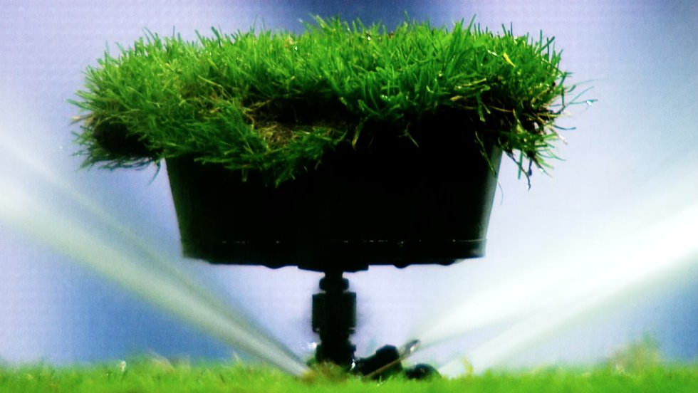 El riego es fundamental para el crecimiento de la planta, pero también para permitir una forma de juego rápida, vistosa y atractiva. Cada club tiene libertad para mojar el césped como desee de cara a un encuentro, pero debe rellenar un informe en el que precise cuánto tiempo regará antes y después del calentamiento previo al pitido inicial y en el descanso. Los aspersores deben ser pequeños para que el jugador no los note y no afecte al desarrollo del juego. ¿Cuánto se debe regar? Un riego corto, de dos minutos antes de un partido, deja aproximadamente medio litro de agua por metro cuadrado. Uno largo, en verano o para algún tratamiento específico, puede alcanzar hasta los 10 litros por metro cuadrado. En su campo, la SD Huesca cuenta con 35 aspersores (en la foto) para regar el terreno de juego después de cada siega y antes de los partidos. Suelen estar escondidos bajo un tepe de césped.