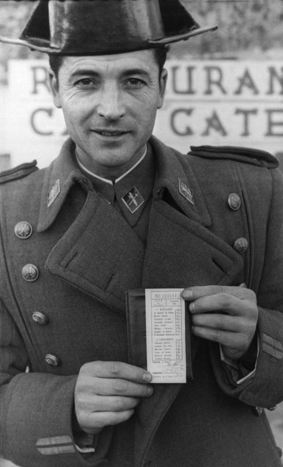 La Quiniela se estrenó el 22 de septiembre de 1946. Se apostaba por siete partidos. Se jugaron 38.530 boletos, con una recaudación de 77.060 pesetas (a dos pesetas cada uno). Los dos acertantes de los siete partidos se llevaron 9.603 pesetas cada uno. “La Quiniela significó un impulso definitivo para el fútbol. Los aficionados tenían un motivo más para interesarse por todos los partidos, y no solo los de su equipo”, valora Alfredo Relaño. En la primera temporada los aficionados tenían que acertar el ganador del partido y el número de goles que metería cada equipo. A partir del año siguiente se introdujo el sistema de 1X2 que ha llegado hasta nuestros días. En la foto, el brigada de la Guardia Civil Luis Álvarez Perera con el boleto en la mano. Fue el único máximo acertante de la jornada 16 en la temporada 195051.