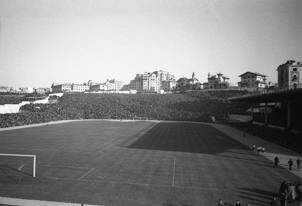 Los diez estadios en los que se disputó la primera temporada del campeonato tenían una capacidad media de 16.500 espectadores. Allí estaban el viejo San Mamés, Sarriá, el estadio de Chamartín o el Metropolitano. No tenían iluminación porque no se jugaban partidos de noche. “Solían construirse a las afueras de las ciudades, aunque muchos parecen céntricos hoy. Antes eran los barrios los que daban nombre a los campos. Ahora son los campos los que dan nombre a los barrios”, comenta Alfredo Relaño, director del diario 'As'. El Metropolitano sufrió graves daños durante la Guerra Civil y fue reabierto el 21 de febrero de 1943, en un derbi liguero entre el Atlético y el Real Madrid (2-1, en la foto). No había asientos, prácticamente todo el público veía el partido de pie en la grada.