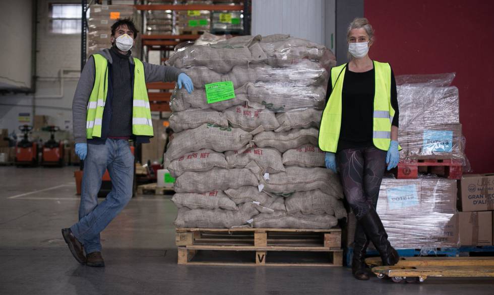 Dos colaboradores de los Bancos de Alimentos en un almacén con comida empaquetada para ser repartida.