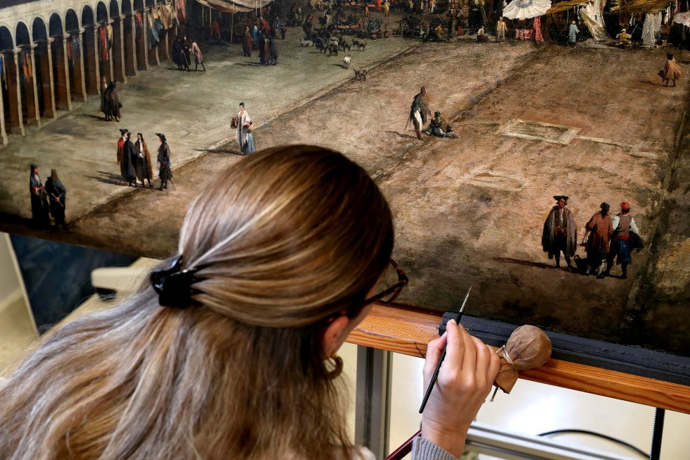 La restauradora Alejandra Martos retoca el cuadro de Canaletto 'Vista de la plaza de San Marcos en Venecia'.