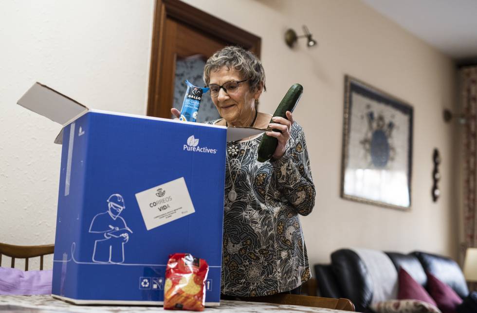 Mª Carmen Clavero, de 84 años, abre el lote de alimentos gratuitos que la iniciativa 'Cestas contra la covid-19' le ha llevado hasta la puerta de su casa.